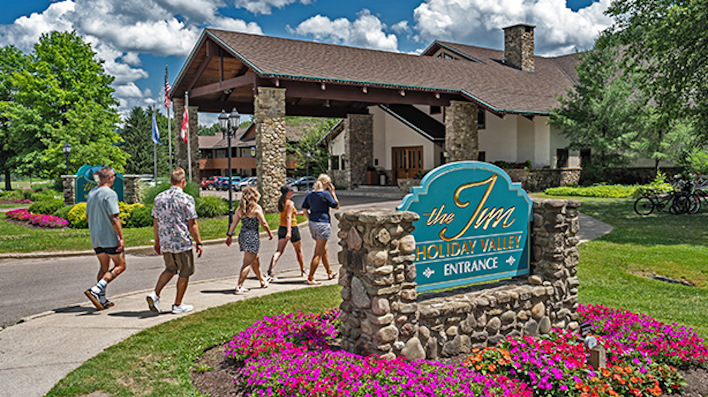 Five people walking towards the entryway to The Inn at Holiday Valley on a sunny summer day. 